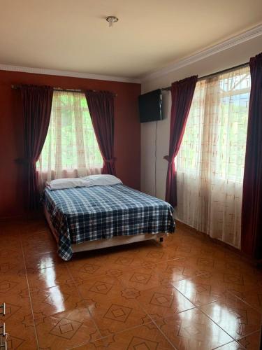 a bedroom with a bed and two large windows at Quinta Doña Adita in Girón