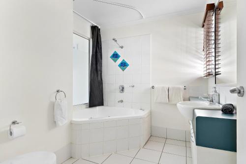 a white bathroom with a tub and a sink at 1 Bedroom Ground Level Unit in Noosaville Resort in Noosaville