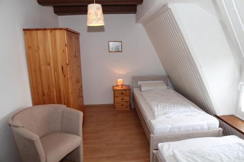 a small bedroom with a bed and a chair at Uttumer Mühle Eiske in Krummhörn