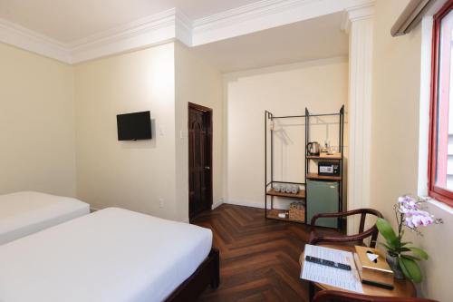 Dormitorio con cama, escritorio y TV en 9 Hostel and Suites en Ho Chi Minh
