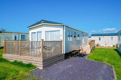 a mobile home with a wooden fence and grass at The Seascape, Padstow in Padstow