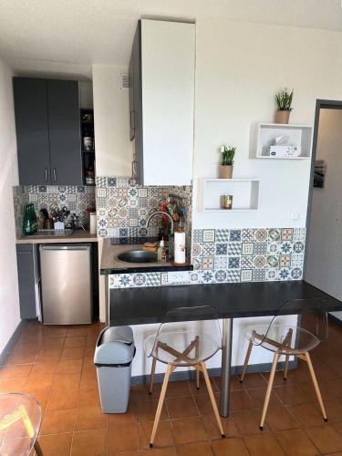 une cuisine avec un comptoir noir et quelques chaises dans l'établissement Résidence Verdon - Magnifique T2, vue mer , à proximité des plages et des commerces MAE-6111, à Six-Fours-les-Plages