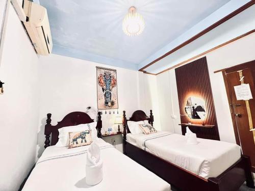 two beds in a small room with white walls at Vangvieng Pool House Hotel in Vang Vieng