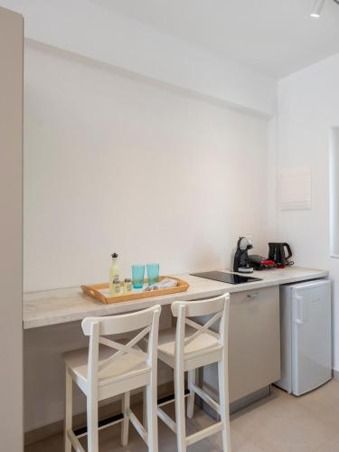 a kitchen with a counter and two stools at Amouage Studios in Kampos Paros