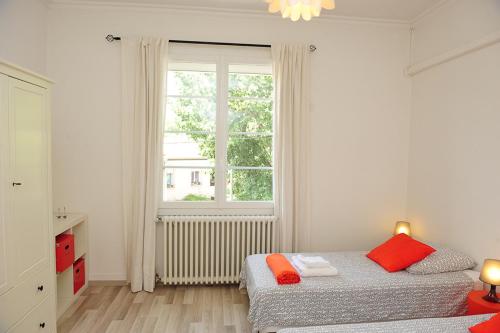 a white bedroom with two beds and a window at Appartement Les Hortensias in Avignon