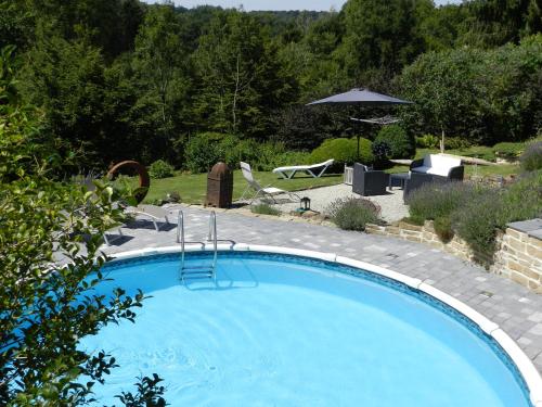 ein großer blauer Pool in einem Hof mit Sonnenschirm in der Unterkunft O Sixième Sens in Williers