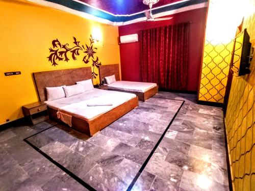 RoyalVilla Guest House Karachi في كراتشي: غرفة نوم بسريرين في غرفة صفراء