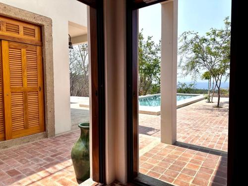 a glass door of a house with a vase next to a pool at Casa Chiquilluma in Piedra Blanca