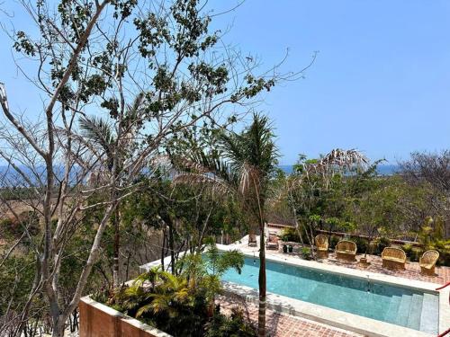 a swimming pool next to a resort with trees at Casa Chiquilluma in Piedra Blanca