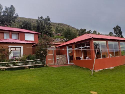 una casa con un patio verde delante de ella en TITIKAKA NATURAL LODGE - LUQUINA en Chucuito