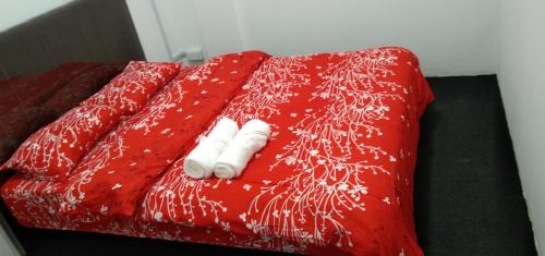 Una cama roja con dos toallas blancas. en Melrose homestay and transport, en Bandar Seri Begawan