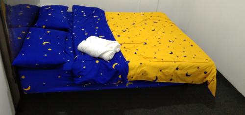 1 cama azul con edredón amarillo y toalla blanca en Melrose homestay and transport, en Bandar Seri Begawan