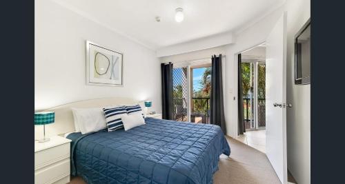a bedroom with a bed with a blue comforter at Blue Waters Apartments in Gold Coast