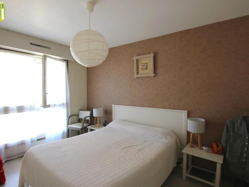 une chambre avec un lit blanc et une grande fenêtre dans l'établissement Appartement T3 au centre, 5 couchages, parking, plage à 70m - FR-1-364-108, à Saint-Brévin-les-Pins