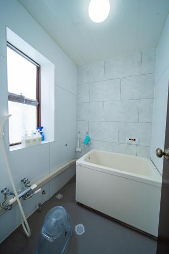 a white bathroom with a tub and a window at FUJIクロスゲートハウス in Fujiyoshida