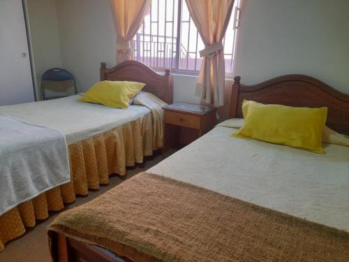 a bedroom with two beds with yellow pillows and a window at Casa Jardin Alameda in Curicó