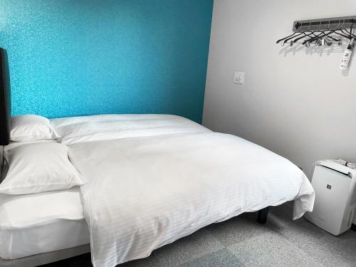 a bedroom with a white bed with a blue wall at Green Rich Hotel & Capsule Naha - Artificial hot spring Futamata Yunohana in Naha