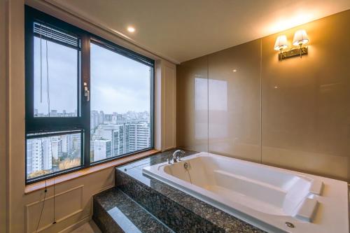een badkamer met een groot bad en een groot raam bij JK Blossom Hotel in Seoul