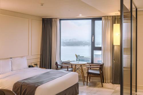 um quarto de hotel com uma cama, uma mesa e uma janela em JK Blossom Hotel em Seul