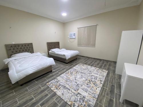 een slaapkamer met 2 bedden en een tapijt bij شقق مساكن الاميره in Yanbu