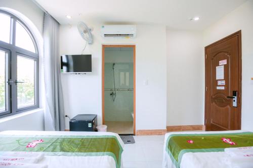 a room with two beds and a tv and a door at ALEX HOTEL and SPA in An Bàn (2)