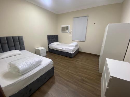 Cette chambre comprend 2 lits et une fenêtre. dans l'établissement شقق مساكن الاميره, à Yanbu