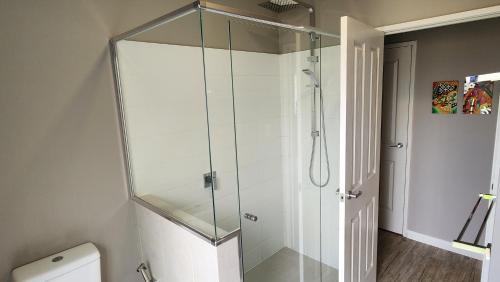 a glass shower in a bathroom with a toilet at Tranquil Gumnut Cottage - Close to Airport in Perth