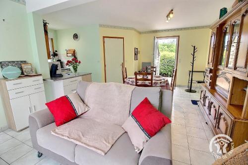 un salon avec un canapé gris avec des coussins rouges dans l'établissement La perdrix, à Lézardrieux