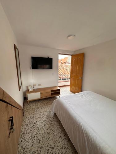a bedroom with a bed and a flat screen tv at Casa Blanca Hostal in Rionegro