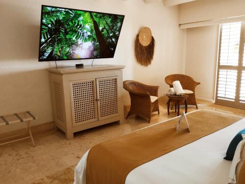 1 dormitorio con TV de pantalla plana en la pared en Hotel Tres Vidas Acapulco, en Barra Vieja