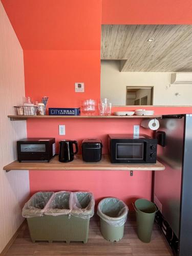 a kitchen with a shelf with two microwaves and two baskets at East Villa Shimanami Mukaishima seafront in Onomichi