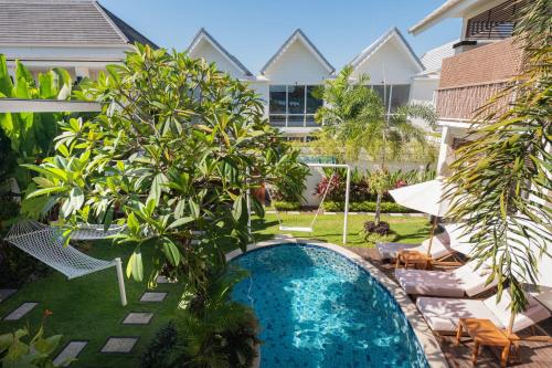 a swimming pool in the yard of a house with trees at Aeera Villa Canggu by Ini Vie Hospitality in Canggu