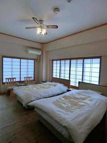 a bedroom with three beds and a ceiling fan at Minshuku Inn Shirahama Ekinoyado in Shirahama