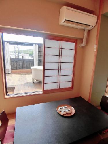 a room with a table with a window and a plate at Minshuku Inn Shirahama Ekinoyado in Shirahama