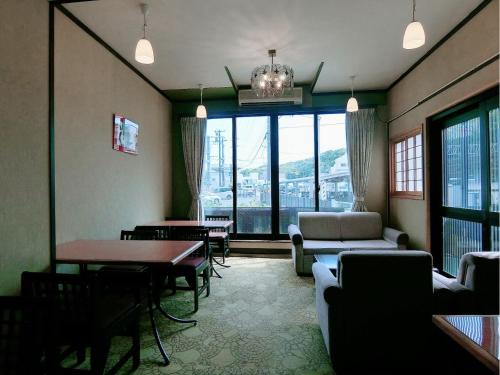a living room with a couch and a table and chairs at Minshuku Inn Shirahama Ekinoyado in Shirahama