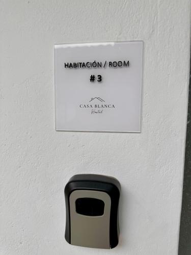 a black and white sign on a white wall with a mailbox at Casa Blanca Hostal in Rionegro