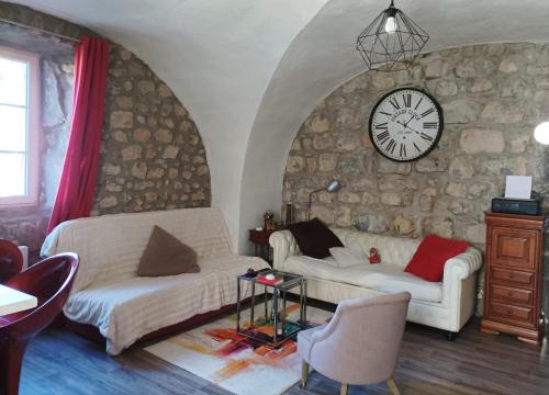 - un salon avec deux canapés blancs et une horloge dans l'établissement Pretty Ardche Apartment Completely Renovated, à Ruoms