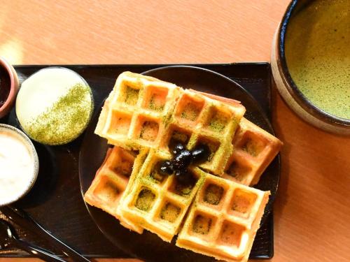 a plate of waffles with syrup on a table at KAYA Kyoto Nijo Castle, BW Signature Collection by Best Western in Kyoto