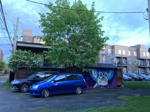 un coche azul estacionado al lado de un edificio con una pintura en Owl House - Hot Tub with rooftop terrasse en Quebec