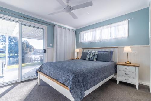 a bedroom with a bed with blue walls and a window at The Waterfront on Teal in Sussex inlet