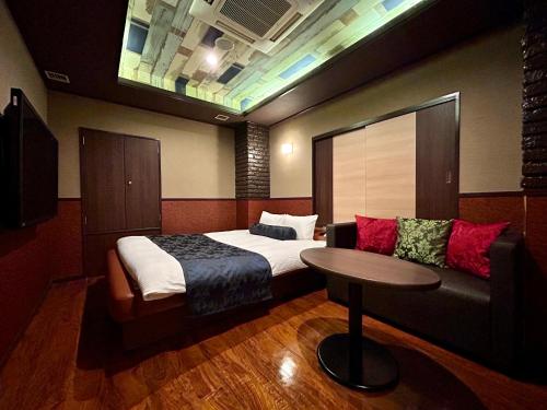 a bedroom with a bed and a table and a couch at Hotel Asian Color (Adult Only) in Tokyo