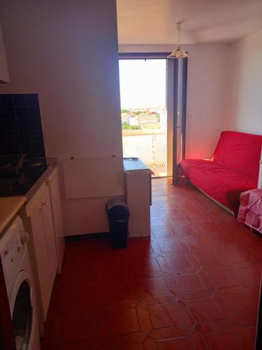 - un salon avec un canapé rouge et une fenêtre dans l'établissement Studio avec petite terrasse proche plage et commerces, à Valras-Plage