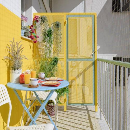 une table sur un balcon avec une porte jaune dans l'établissement Comfy Sunny flat wh balconycenter up to 8ppl, à Athènes
