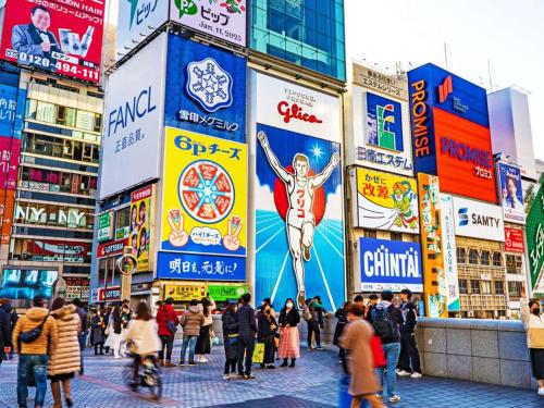 a crowd of people walking in a city with signs at Astil Hotel Shinosaka Precious in Osaka
