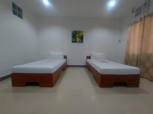 two beds in a room with white walls at RGE Hotel in Belen