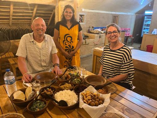 un grupo de personas de pie alrededor de una mesa con comida en Sigiriya Water Cottage en Sigiriya