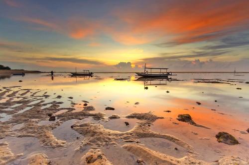 a beach with boats in the water at sunset at Abian Klumpu Villa & Spa Sanur Bali in Sanur