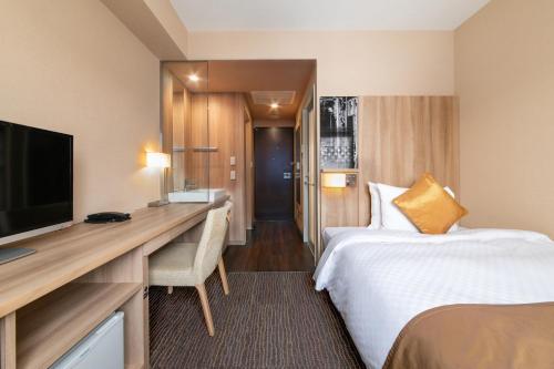 仙台的住宿－仙台遠景酒店，酒店客房配有一张床、一张书桌和一台电视。