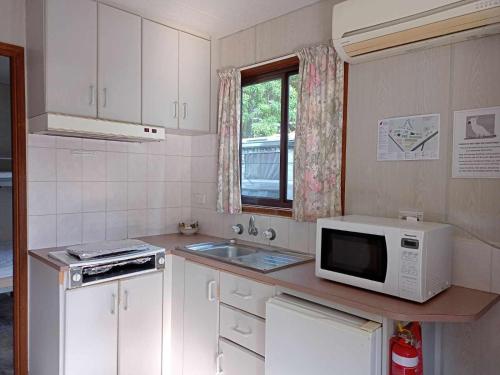 Una pequeña cocina con microondas y fregadero. en Katoomba Falls Tourist Park, en Katoomba