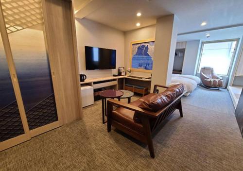 a hotel room with a couch and a bed and a television at Koyado Enn in Toyooka